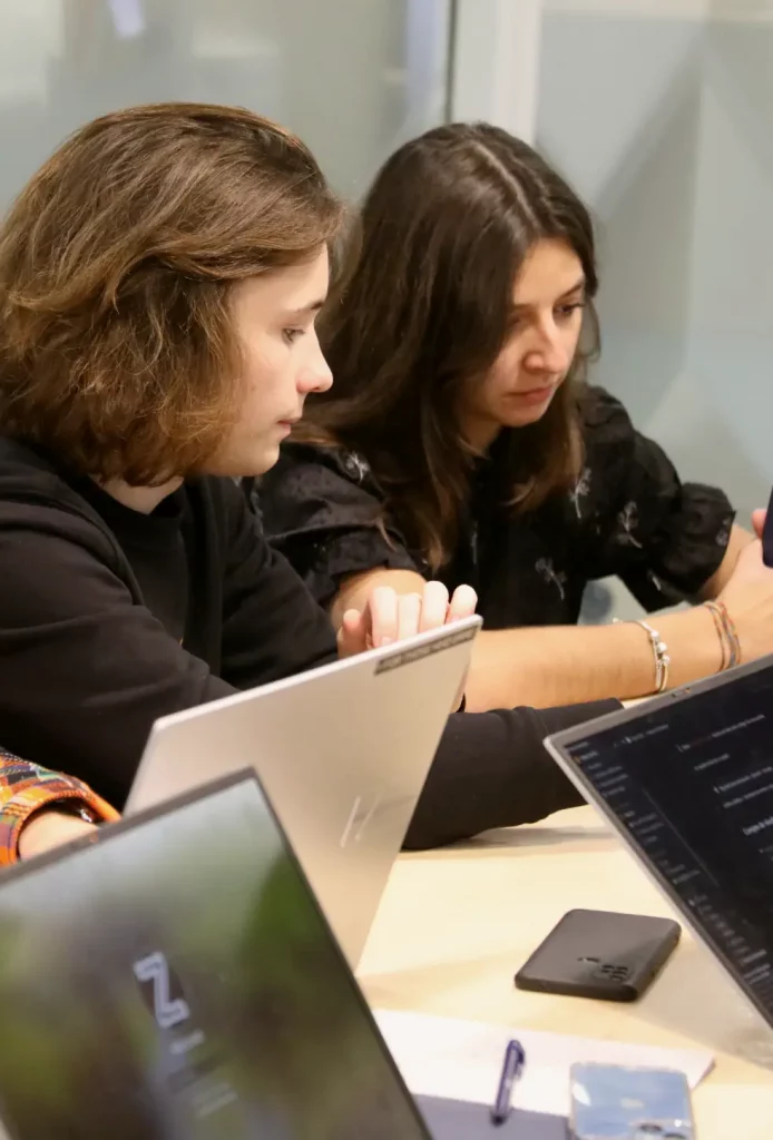 Un étudiant et une étudiante travaillent en groupe, sur leur ordinateur.